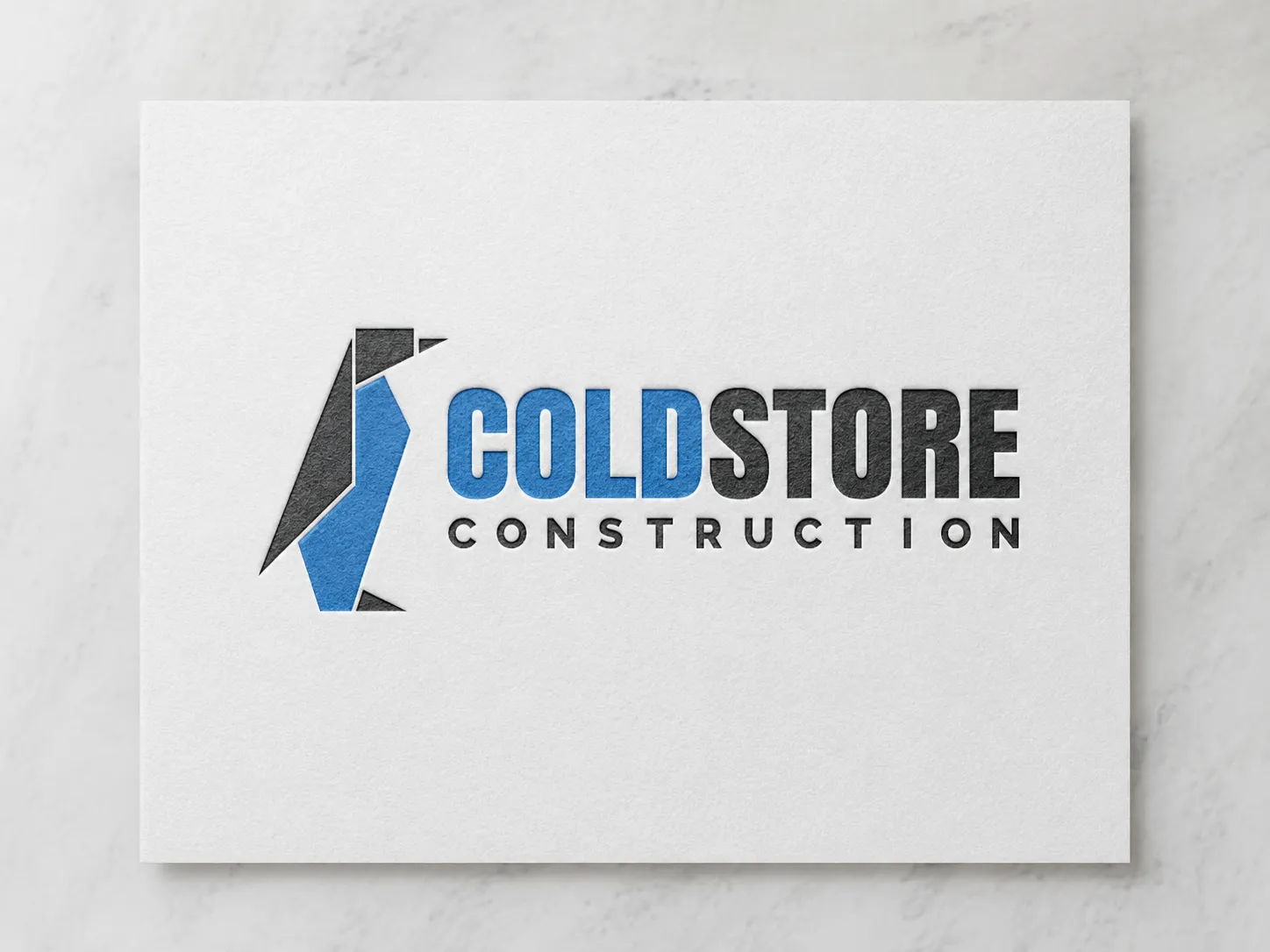 The redrawn Coldstore Construction identity — a sharp, geometric penguin mark beside a bold blue-and-black wordmark, shown letterpressed on paper.