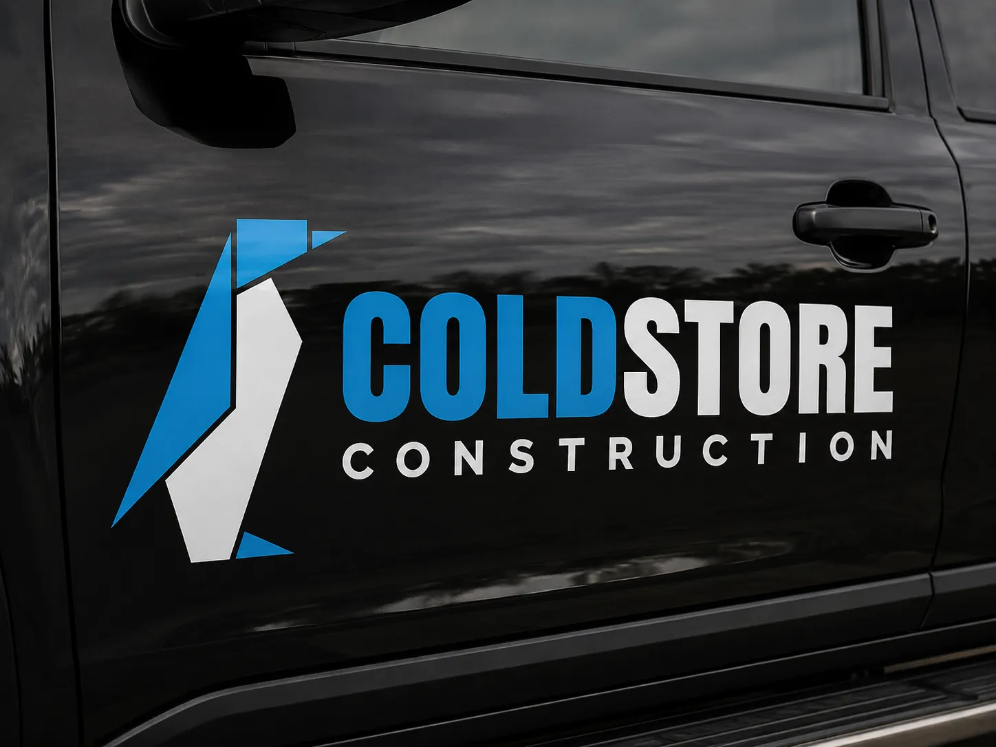 The new penguin mark and wordmark applied large across a black vehicle door.