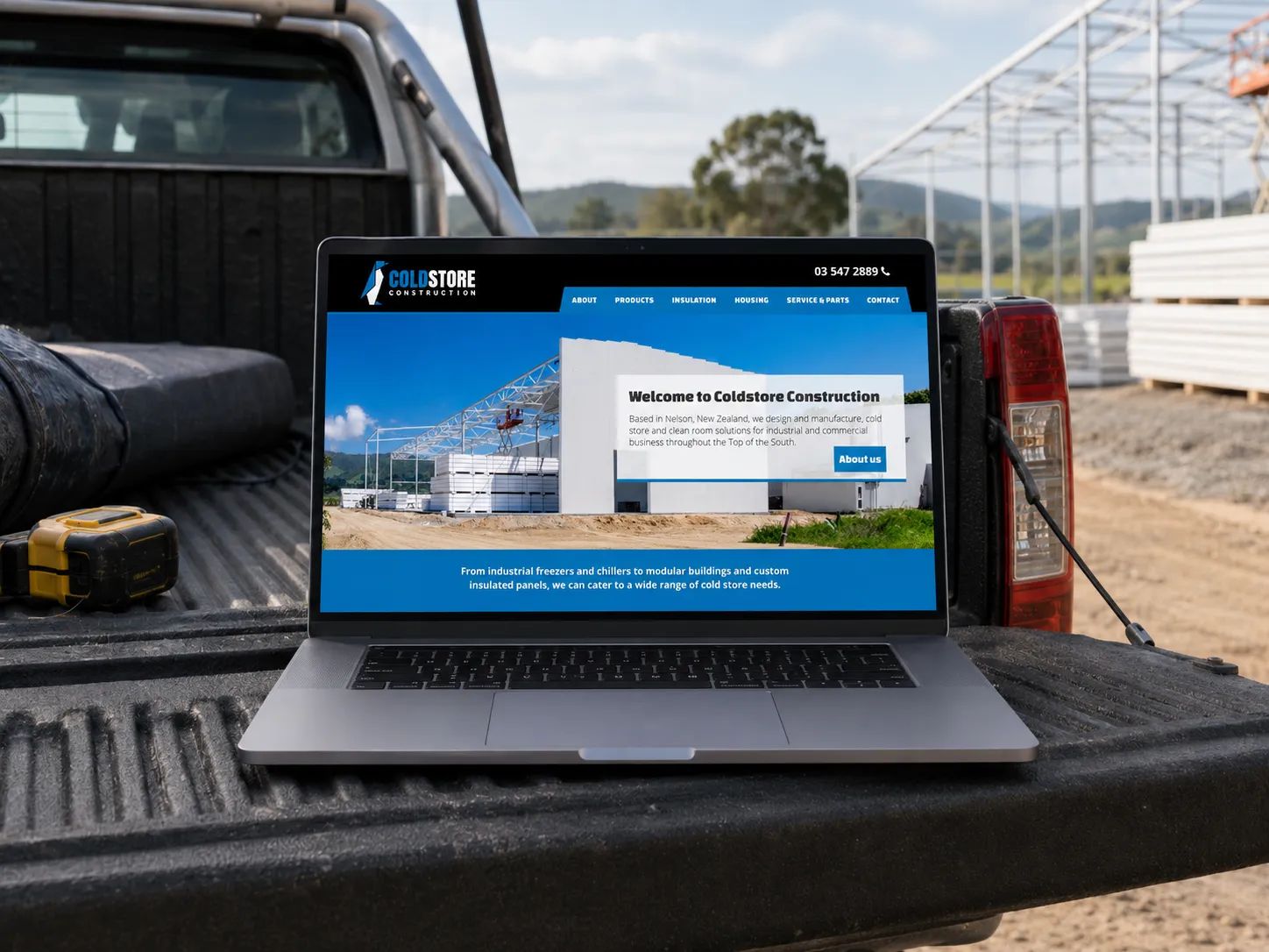 The Coldstore Construction website on a laptop resting on a ute tailgate on site, led by large project photography and clear service messaging.