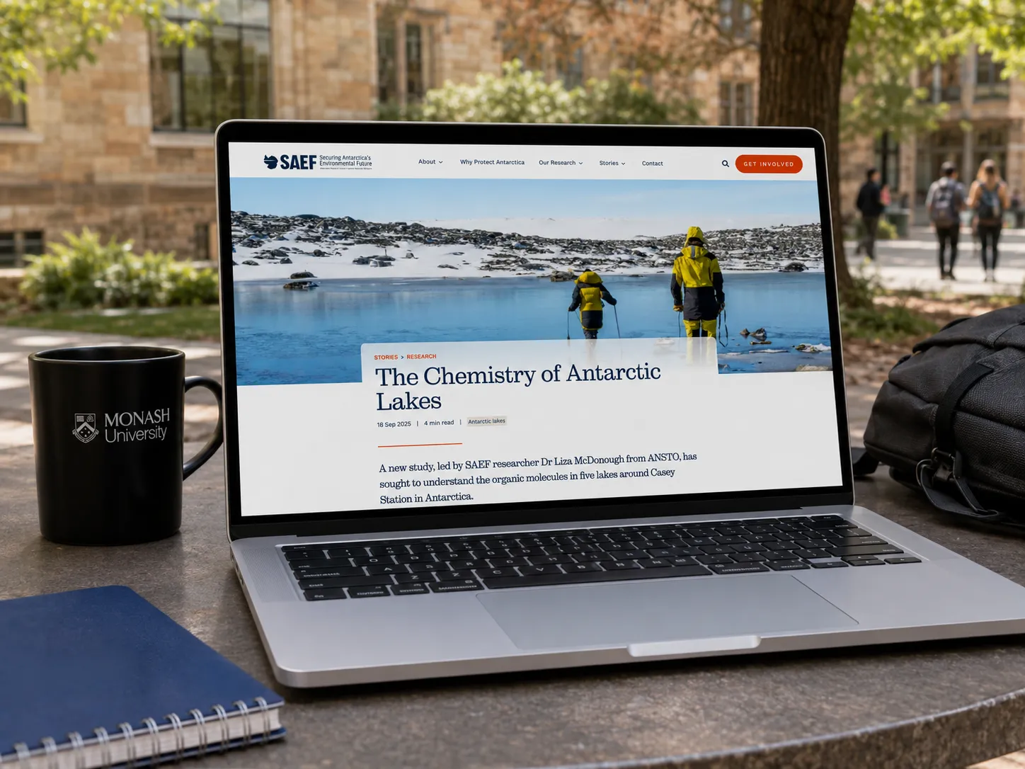 A SAEF research story, 'The Chemistry of Antarctic Lakes', on a laptop on a Monash University campus table.